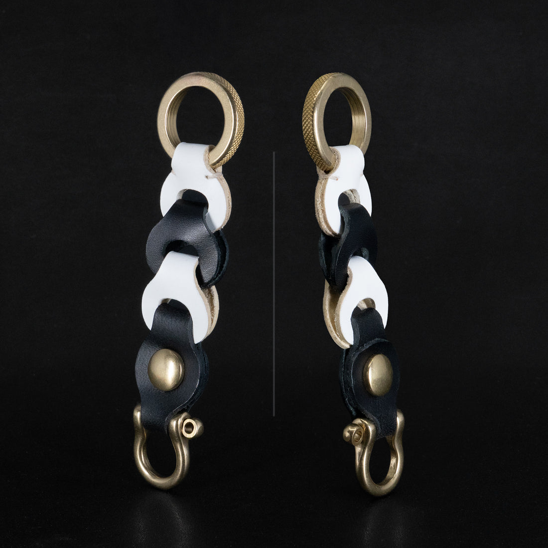 Black and white leather link keychain, both sides shown, with brass ring and shackle clip